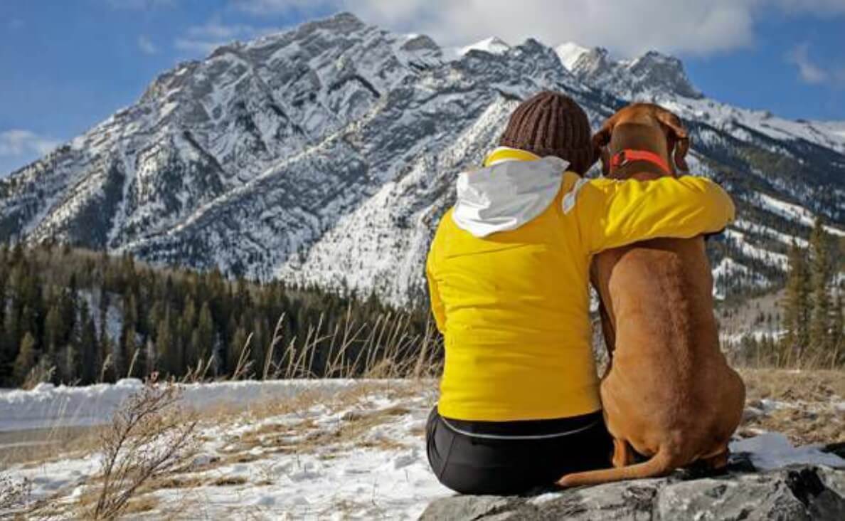 woman hugging dog looking at a mountain