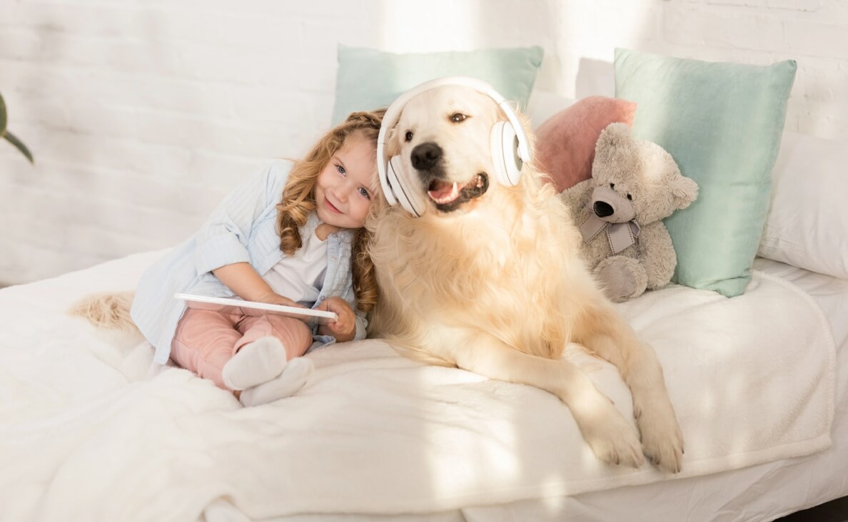 DO DOGS LIKE MUSIC - little girl and golden retriever on bed listening to music