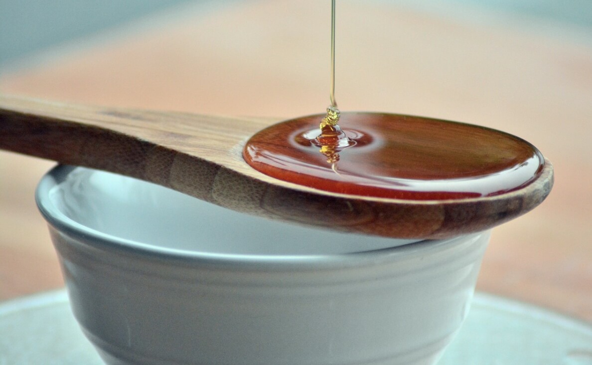 Can Dogs Eat Honey - honey in wooden spoon over bowl